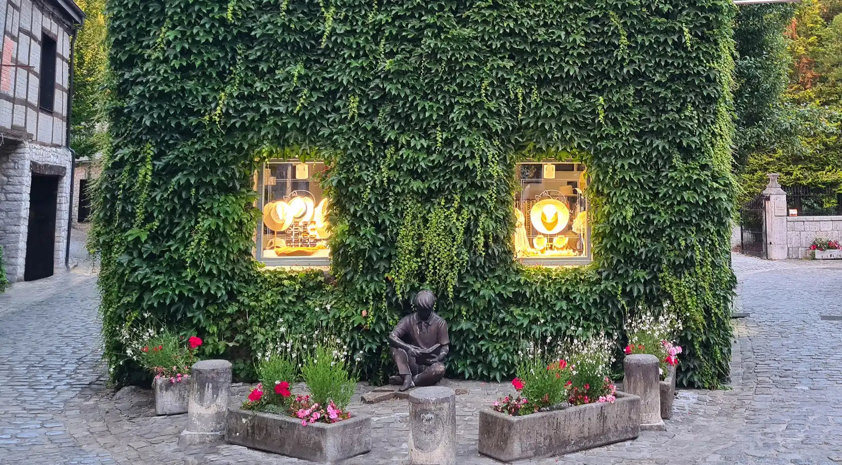 Bâtiment recouvert de lierre avec des fenêtres illuminées et une statue. Bâtiment recouvert de lierre avec des fenêtres illuminées et une statue.